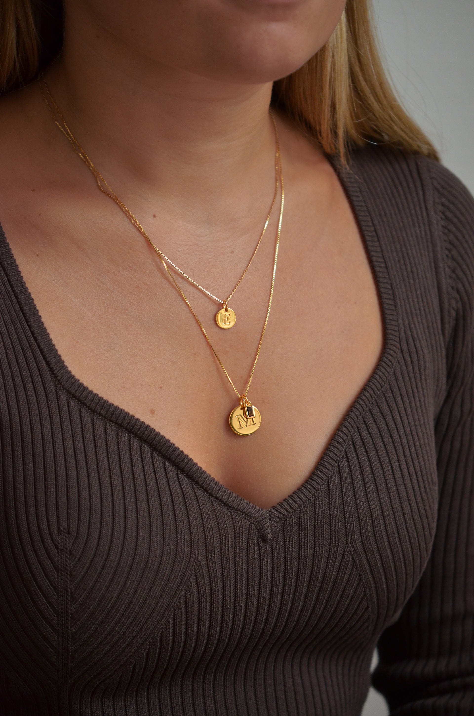 One short gold chain with gold mini letter, medium gold chain with a big gold letter and a gold pandant with brown details