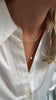 A short gold necklace with more small pearls on it and a longer charm necklace with one pearl on and the chain with its tiny, shining dots.