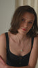 A silver necklace featuring a sparkling star pendant with a crystal, layered with a longer silver necklace, and paired with small silver hoop earrings.