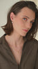 Gold pearl earrings, leaf-design gold bracelet, and layered fine gold necklaces.